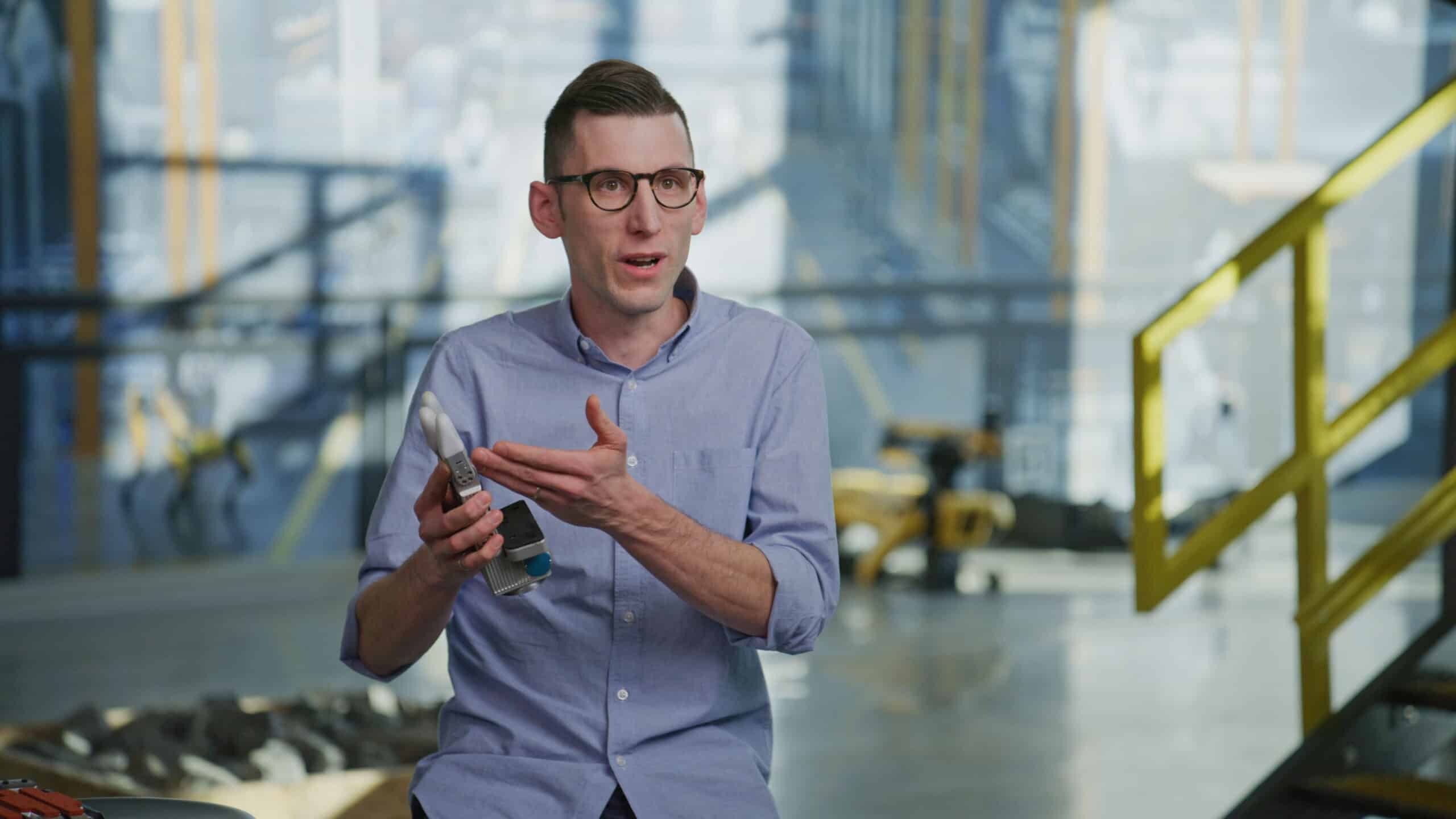 Man holds up a robotic hand.