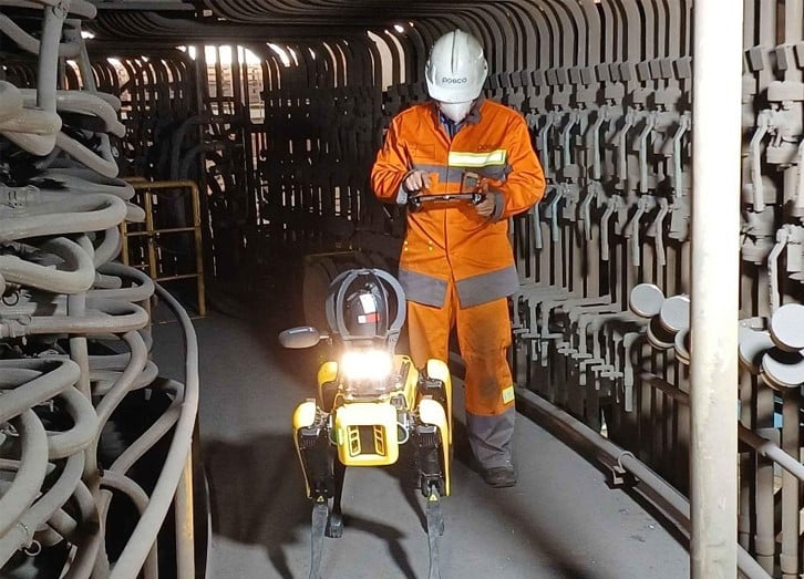 An operator in PPE sets up an autonomous mission, using the tablet controller to control Spot